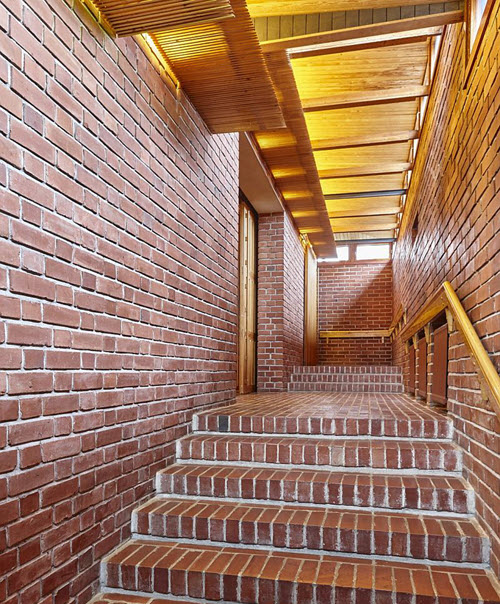 Red brick walls and staircase with wooden roof interior corridor